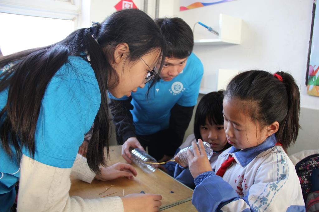 物理学院学生指导小学生制作回滚筒