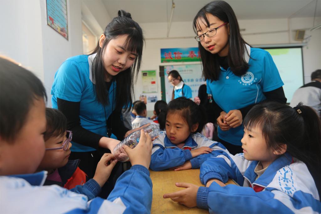 物理学院学生指导小学生制作回滚筒
